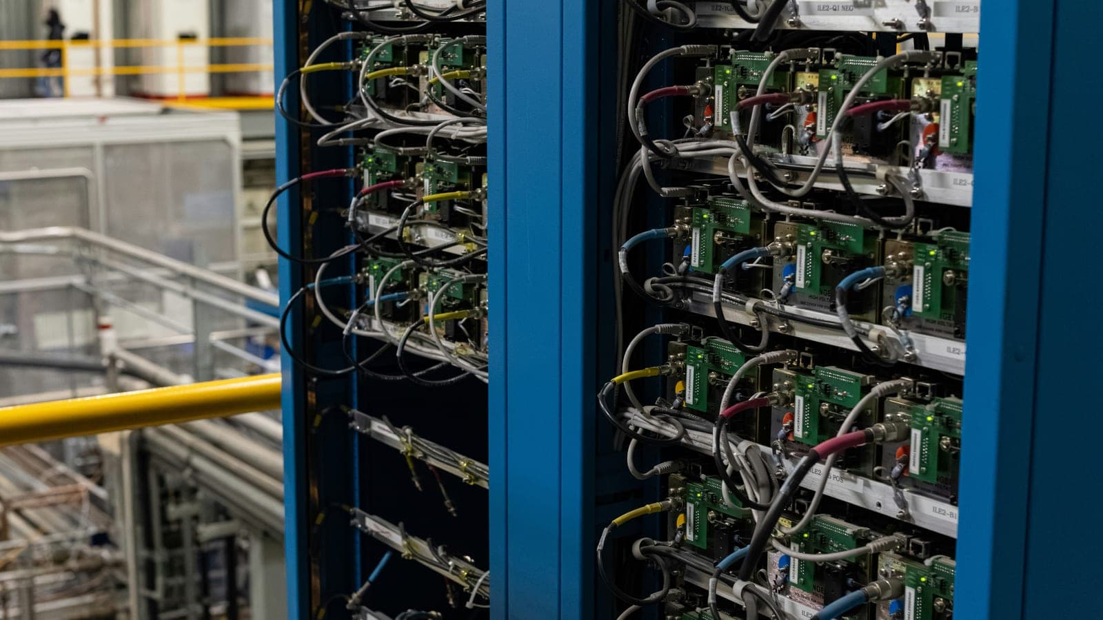 Two blue equipment racks filled with electronic modules and wiring in a laboratory.