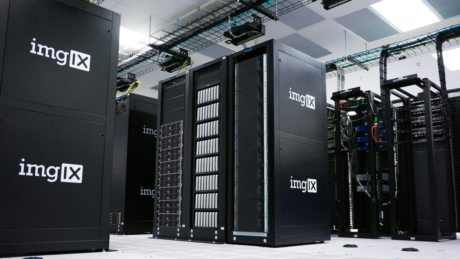 Rows of black server cabinets beneath overhead cable trays.