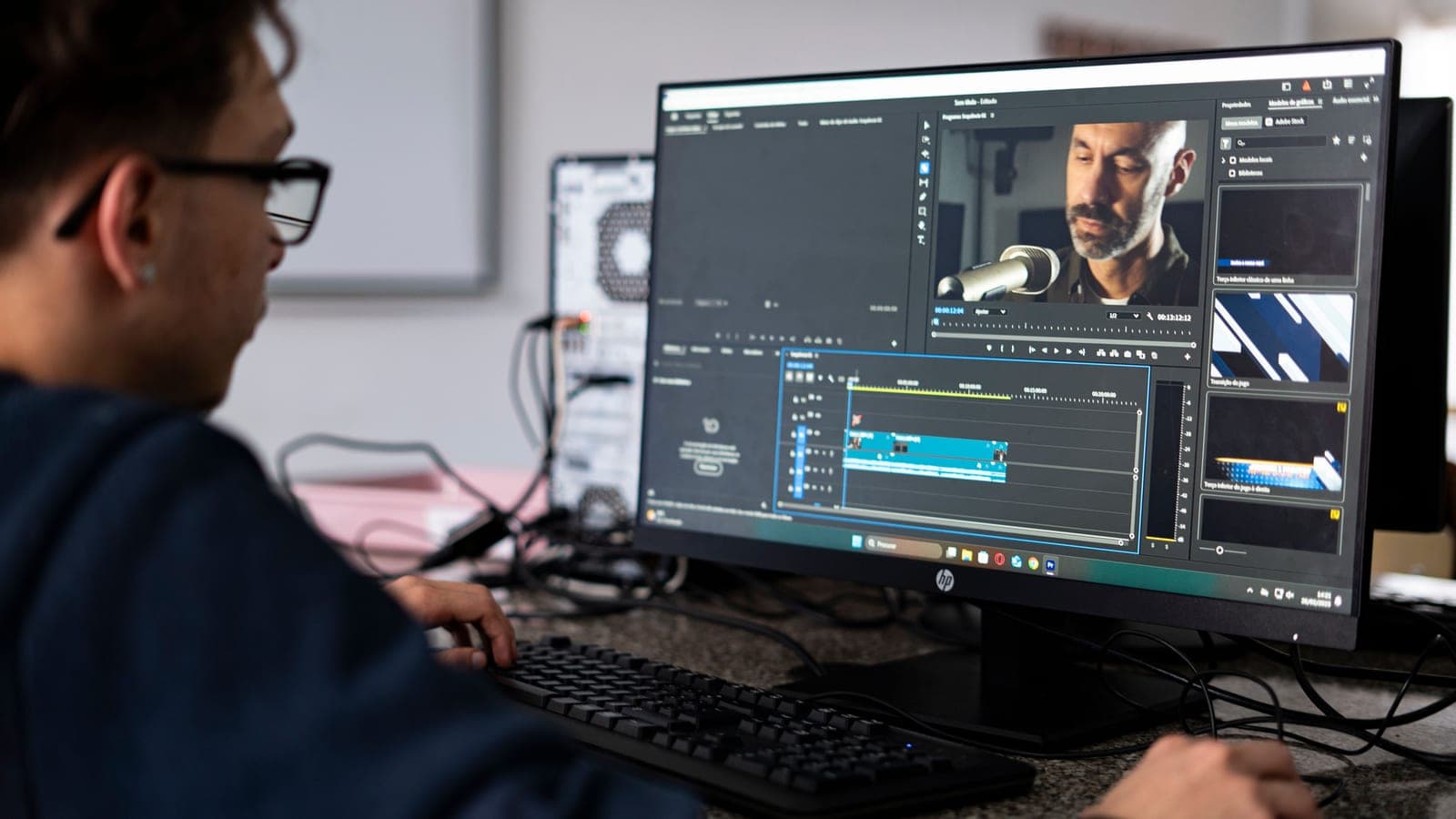 A video editor works at a desktop monitor showing a preview and editing timeline.